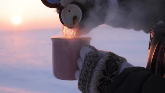 下雪天将茶从热水瓶倒入杯子中