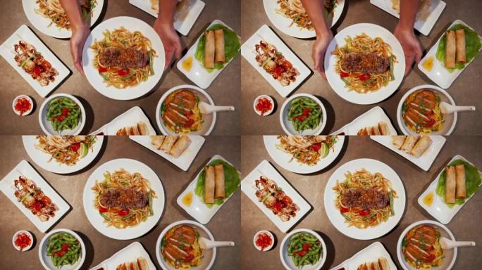 传统的亚洲餐，桌上有烤牛肉和豆芽。在多个盘子上供应亚洲菜肴和开胃菜的俯视图