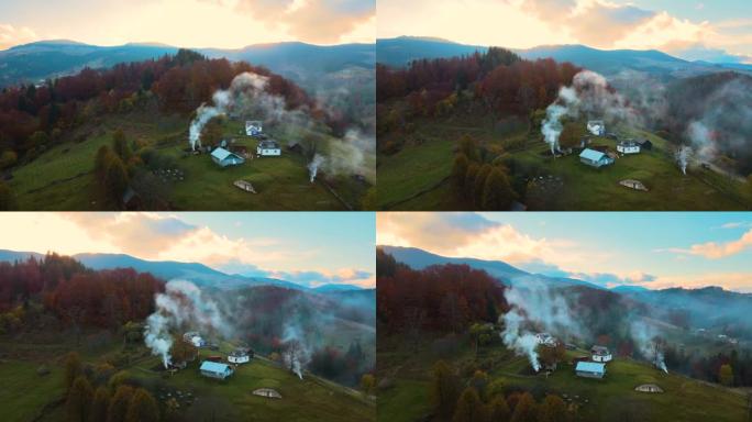 鸟瞰遥远的村庄，在日落时乌克兰喀尔巴阡山脉的秋天森林树木之间的宽阔山丘草地上有小牧羊人的房子。