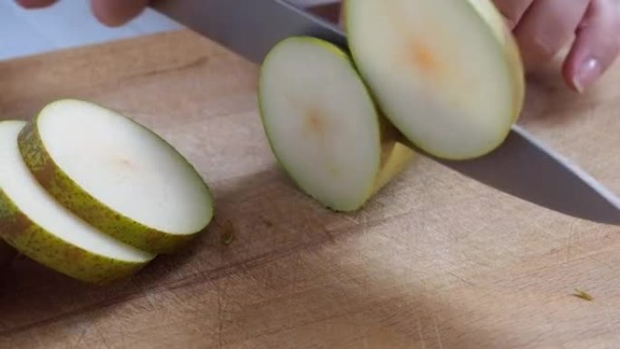 成熟的梨子会议用刀在木砧板上切成薄片。
