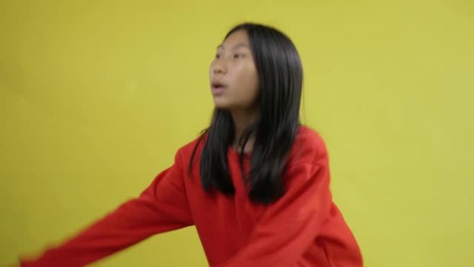 快乐的亚洲女孩穿着黄色背景的红色毛衣唱歌跳舞，生活方式概念。