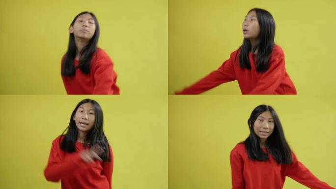 快乐的亚洲女孩穿着黄色背景的红色毛衣唱歌跳舞，生活方式概念。