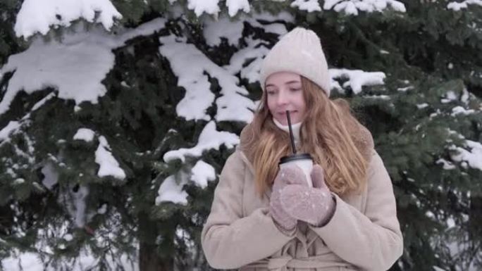 美丽的女人在寒冷的冬天外面喝杯热饮。