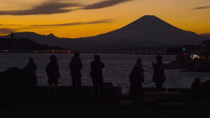 人们在拍照。从稻村加崎黄昏的富士山和江之岛