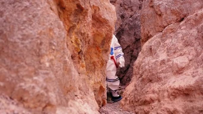 穿着太空服的女人从洞穴里走槽，看到在沙漠地区探索火星的新方法，梦想着人类能遇到水源，生命。