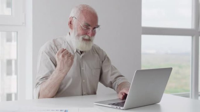 极度快乐满意的老人在笔记本电脑上打字是手势，成功