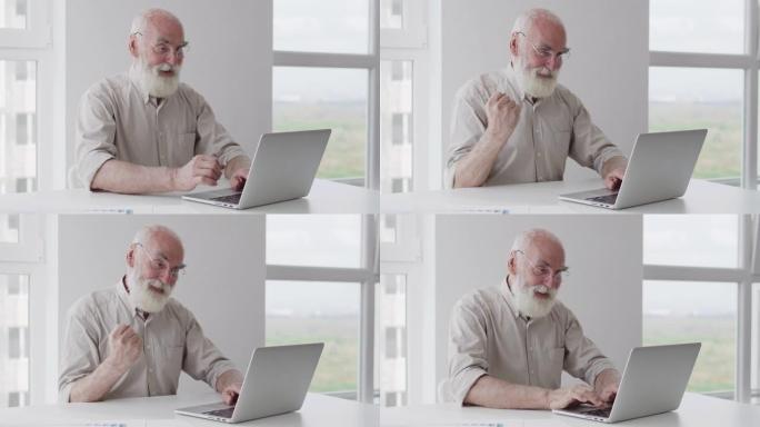 极度快乐满意的老人在笔记本电脑上打字是手势，成功