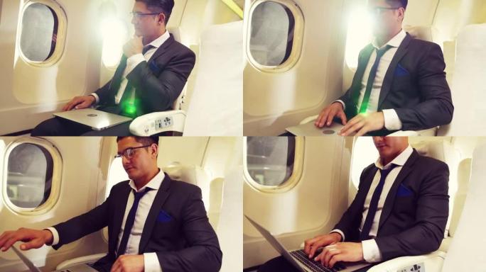 在飞机上使用笔记本电脑的年轻商人