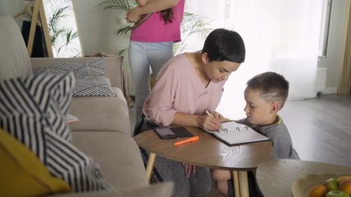 母亲与男孩在餐桌旁画画，而女孩与小猫玩耍