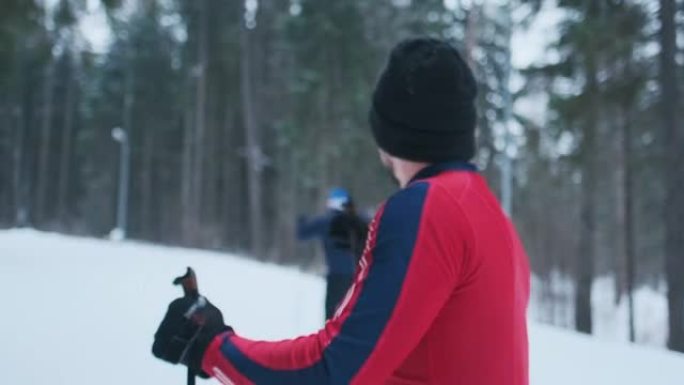 滑雪者谈话愉快。穿着红色滑雪服的年轻人站在越野滑雪道上，笑着看着镜头