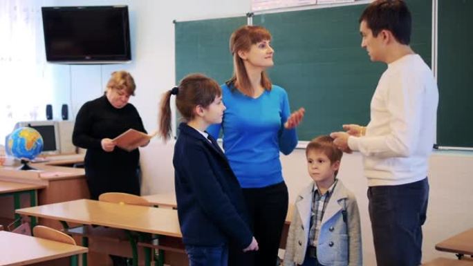 父母在教室里和老师在背景下与孩子交谈。学校的家庭。