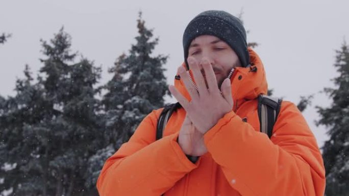 一名30多岁的男子在下雪的冬天，穿着一件鲜艳的橙色夹克，试图给他们热身。