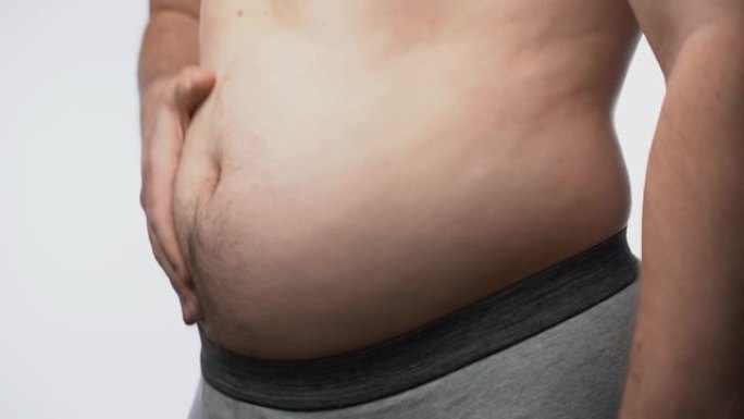 一个大男性胃的特写。胖子检查他的腰f