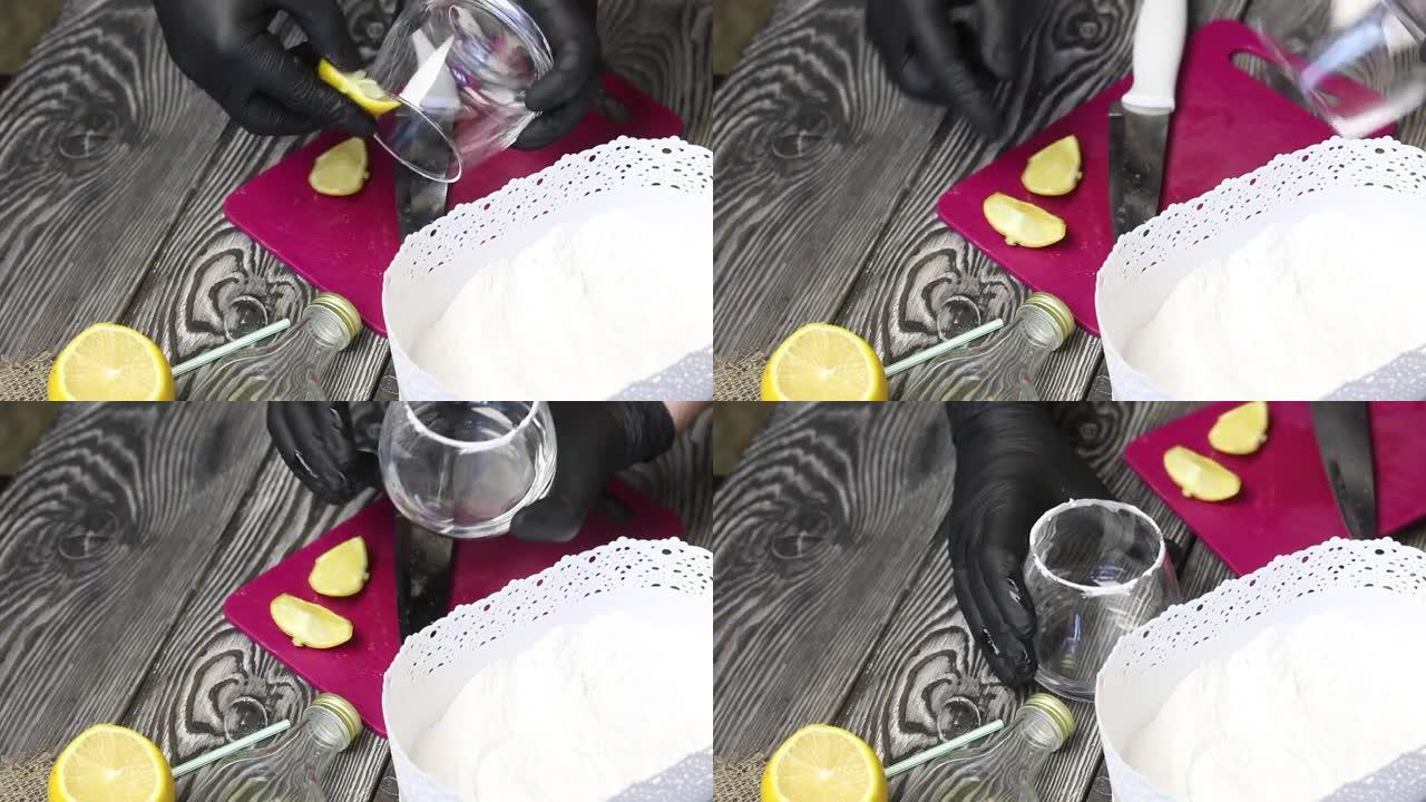 男人用柠檬润湿玻璃杯的边缘，然后将其浸入糖粉中。准备一杯牛奶猕猴桃