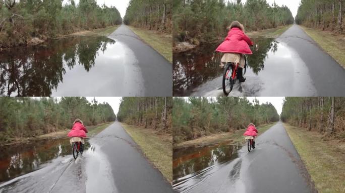 漂亮的年轻女孩在洪水泛滥的小路上骑自行车
