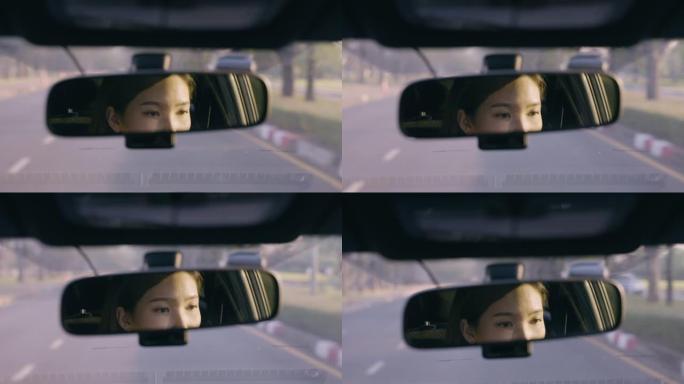 特写镜头亚洲女子驾驶汽车在道路上倒映在后视镜中