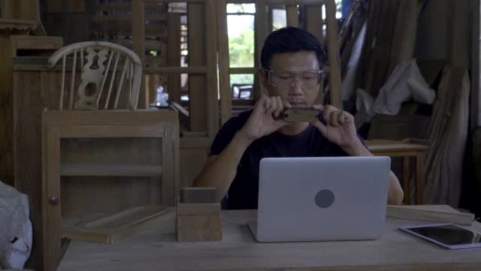 男人是手握平板电脑的熟练木匠，在网上卖木家具，在网站上卖东西