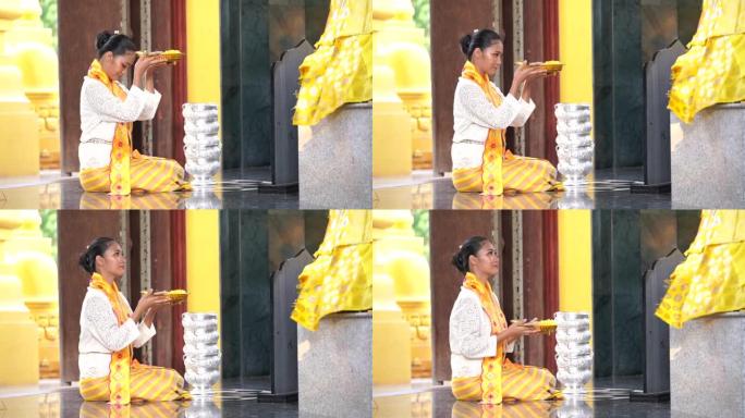 缅甸妇女在寺庙里表达敬意。穿着缅甸传统服装的东南亚年轻女孩参观了一座佛教寺庙。