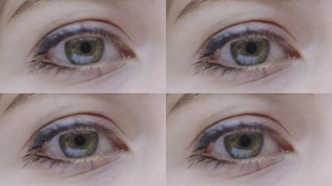 特写女性绿眼看镜头和眨眼，视力手术和干眼症概念