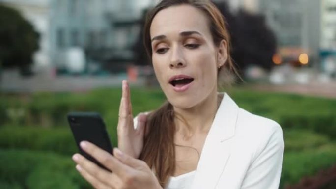 恼怒的女商人在city walk的智能手机上通过视频通话发誓。