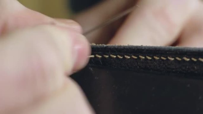 制革商缝制皮革工件。在一个小型工厂特写中手工制作