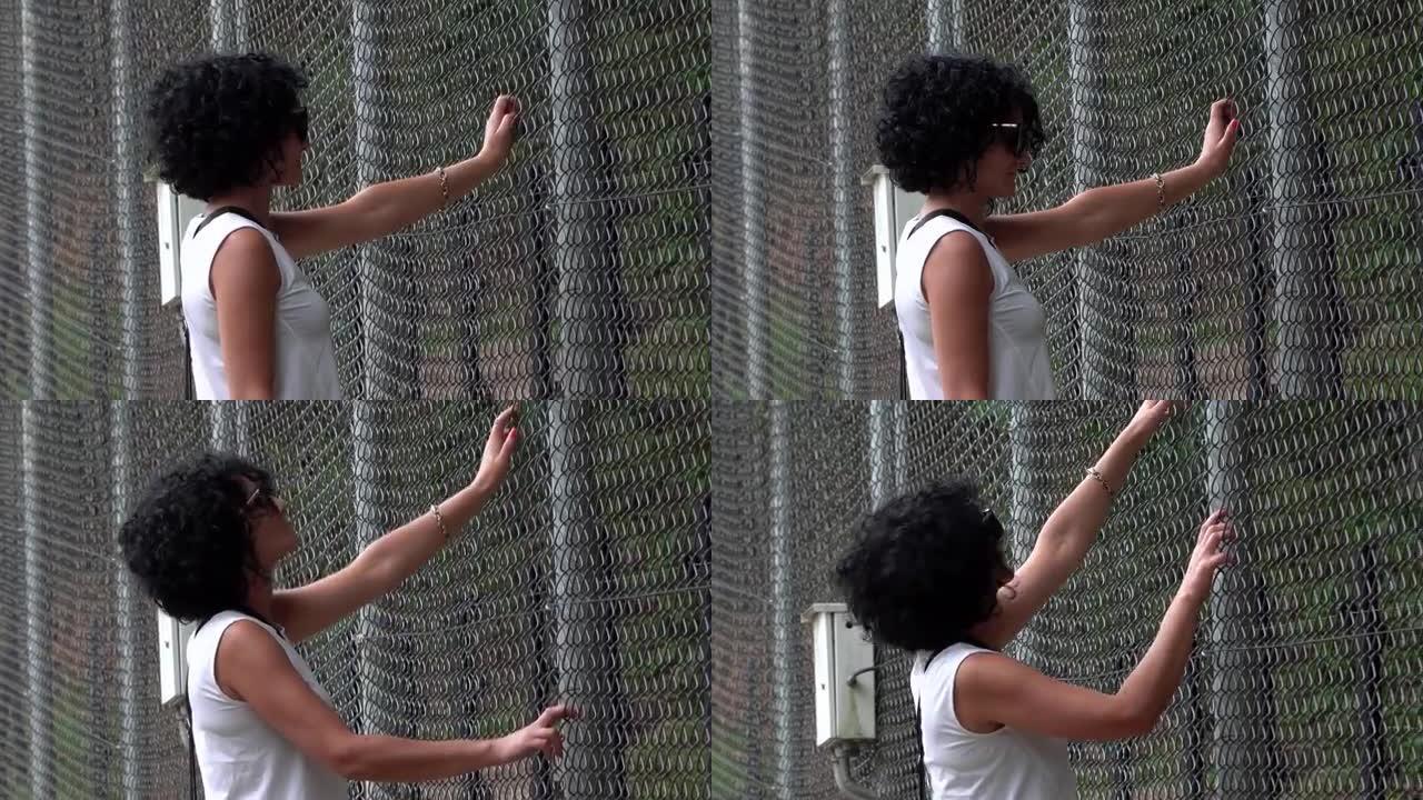 难民妇女把手放在金属栅栏上