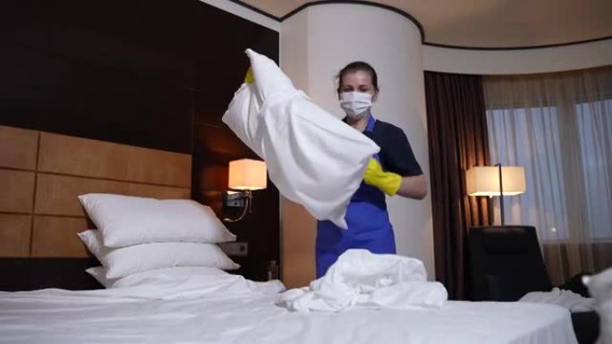 戴着面具和手套的酒店女仆更换床单