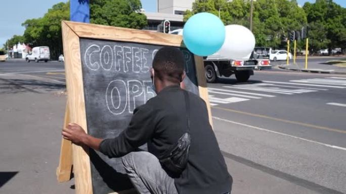 服务员在街上的黑色粉笔板上为他们的咖啡店写字
