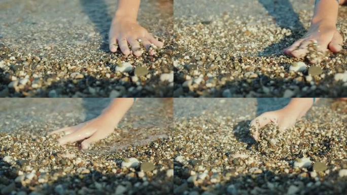 女人的手在海边的浅卵石里找东西