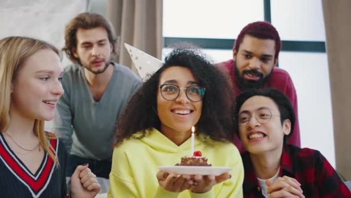 年轻的混血朋友的肖像在镜头中摆姿势，并祝贺他们的朋友生日快乐。一个非裔美国女孩庆祝自己的生日，并在生