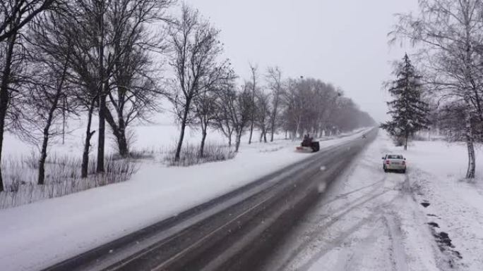 吹雪机平地机清除积雪覆盖的乡村道路鸟瞰图。