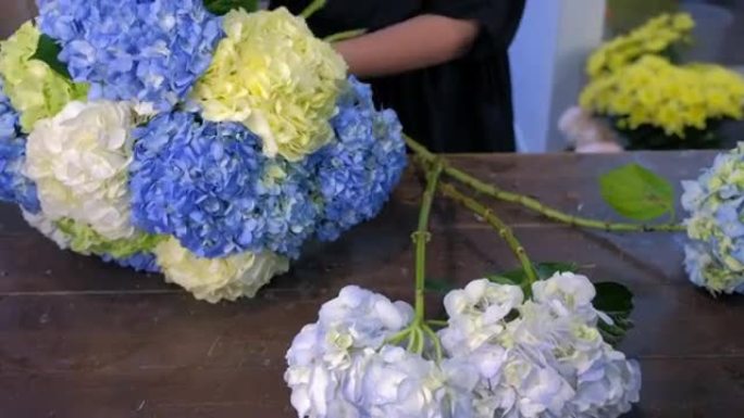 花店妇女在商店里制作大花束绣球花，双手特写。