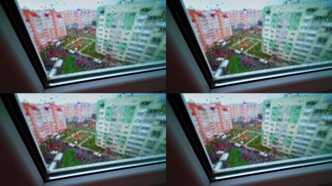 外面有雨的天气。透过窗户，在城市五颜六色的建筑物的背景下，玻璃上有雨滴。