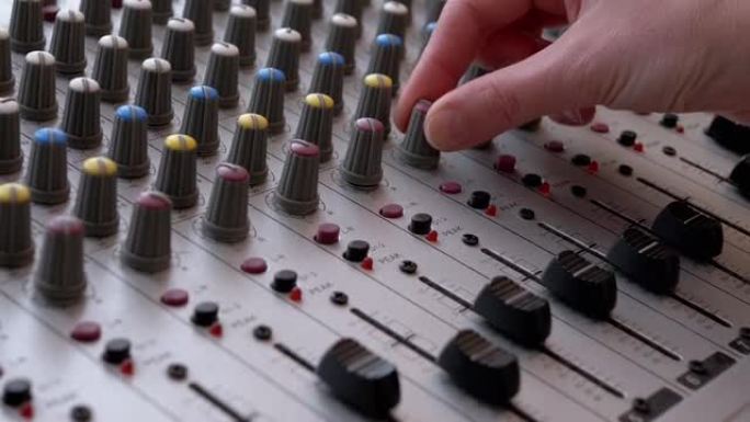 录音师，DJ在录音棚用手指在调音台上移动滑块