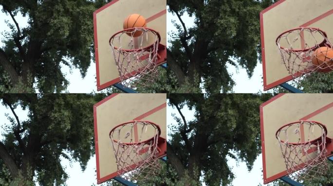 在公园的街头球场上，橙色篮球击中篮筐的特写镜头。击中目标。达到目标