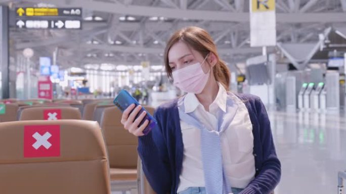 20-30岁的亚洲裔女性在新冠肺炎疫情下使用智能手机在机场旅行，新冠肺炎封锁和旅行重新开放后的新常态