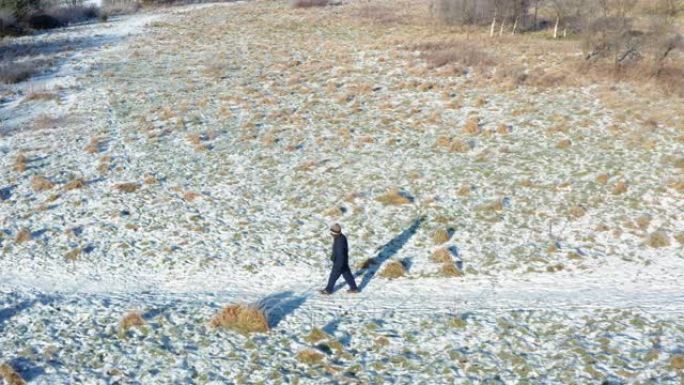 在苏格兰西南部积雪覆盖的人行道上，一名高级男子独自行走时，无人机的高角度视图
