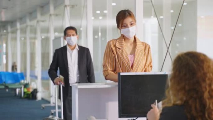 亚洲女性旅客将护照交给航空公司值机柜台的女工作人员，以便签发机票登机牌。女孩戴口罩预防冠状病毒大流行