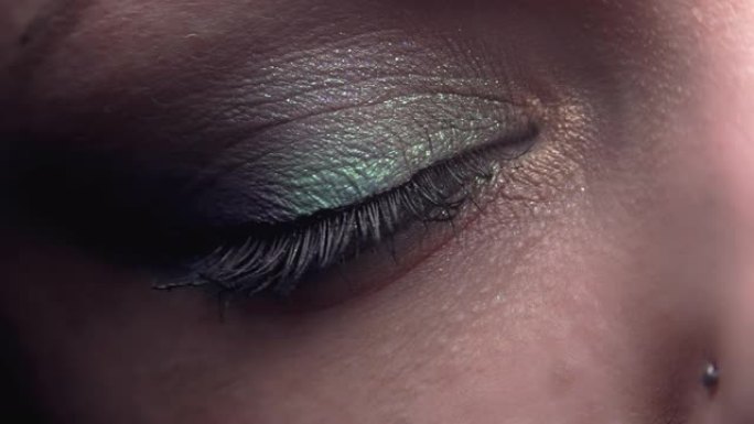 女性眨眼。化妆漂亮，阴影闪闪发光的女人。女人的绿眼收缩。美容、化妆品概念。