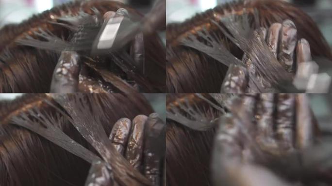 理发师手上的特写镜头。大师在一家美容院用黑色画女孩的头发