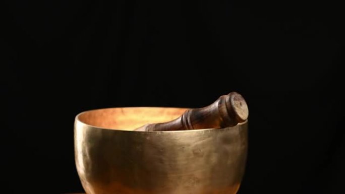 铜唱歌碗在黑色背景上绕其轴旋转。用于冥想和替代医学的藏族乐器