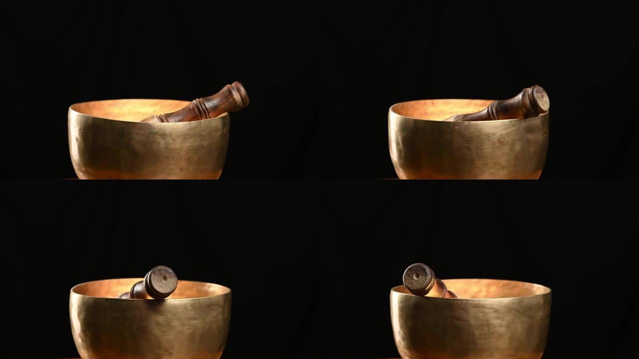 铜唱歌碗在黑色背景上绕其轴旋转。用于冥想和替代医学的藏族乐器