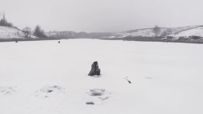 冰冻冰湖冬季捕鱼的概念。渔民正在冰洞里钓鱼。男子用钓鱼竿抓鱼
