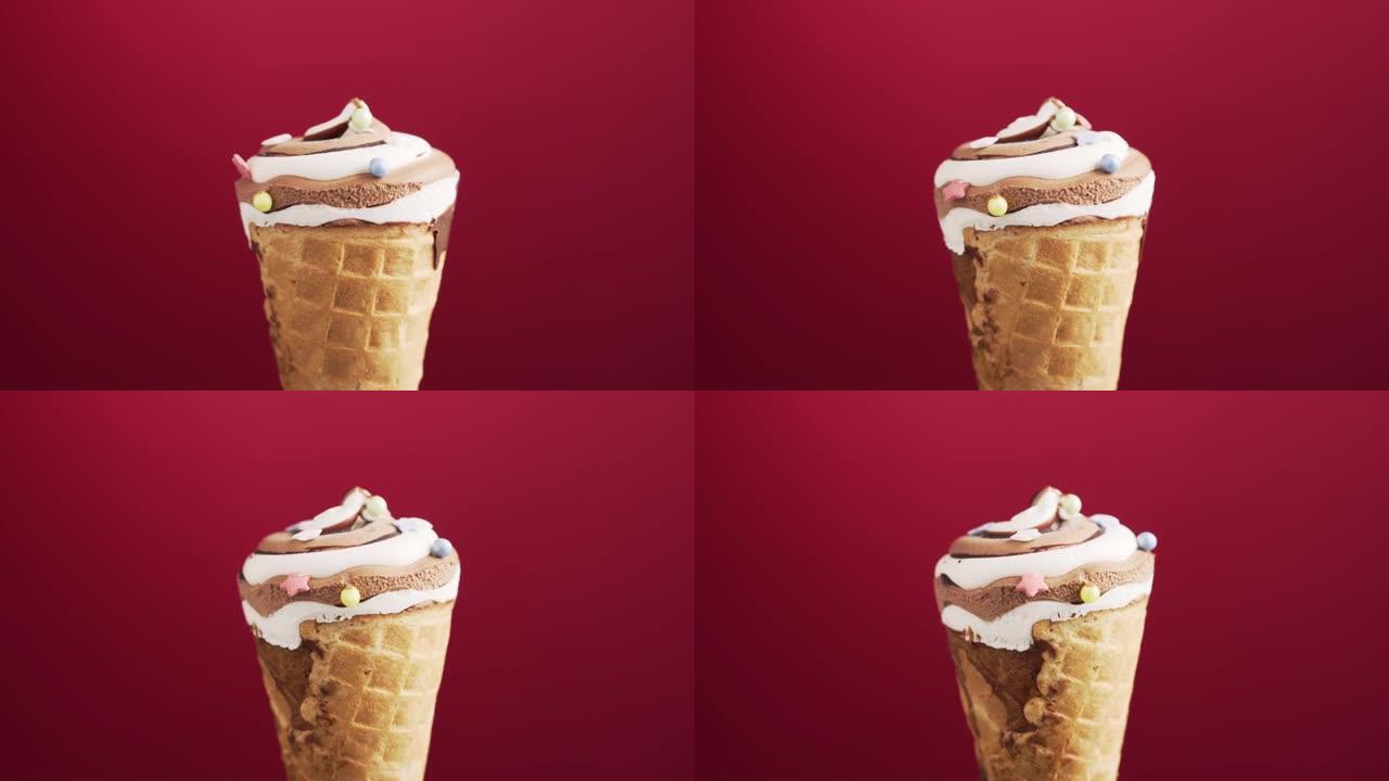 巧克力冰淇淋蛋卷在红色背景上旋转。五颜六色的糖洒在美味的自制咖啡冰淇淋上。
