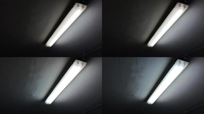 破碎的闪烁荧光灯在地下停车场的黑暗房间的天花板上闪烁