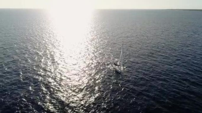 在阳光下在地中海中部航行的帆船无人机的鸟瞰图。我们可以看到整个地平线上的船和水以及水中光线的反射4K