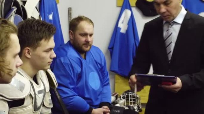Male Coach Talking with Hockey Athletes in Locker 