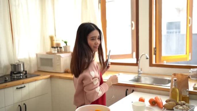 年轻的亚洲妇女在厨房听音乐