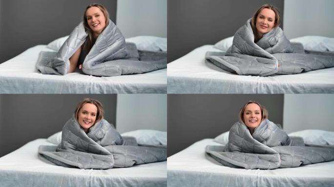 快乐的欧洲女士微笑着躺在床上舒适温暖的格子。4k龙红相机