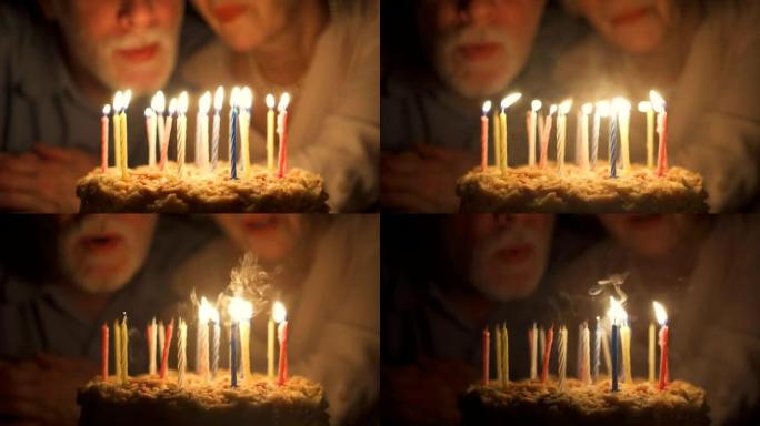 充满爱心的高级夫妇晚上在家用蛋糕庆祝周年纪念日。吹灭蜡烛。